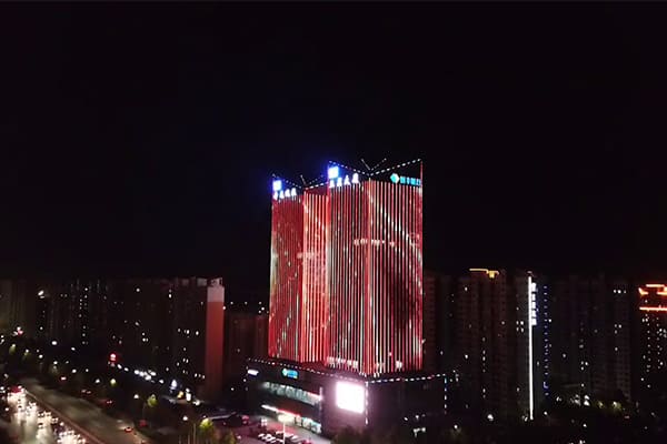 A building facade covered in pixel dots displaying a colorful animation